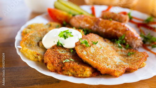 potato pancakes with fried sausages on a white plate