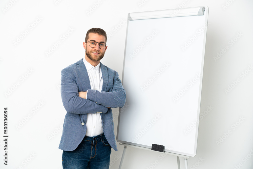 Young handsome caucasian man isolated on white background with arms crossed while giving a presentation on white board Young handsome caucasian man isolated on white background with arms crossed while giving a presentation on white board