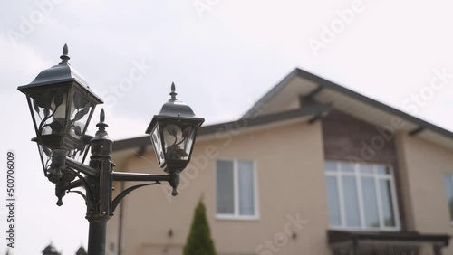 Wallpaper Mural Forged black retro lantern with glass plafond and led bulbs against the backdrop of blurred residential building with windows. Light decoration of the yard, thin cobweb on a pole. Torontodigital.ca