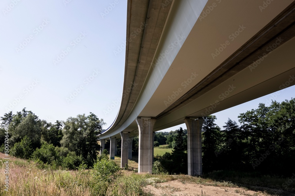 Bottom view of modern highway bridge with concrete pillars as a way of transportation