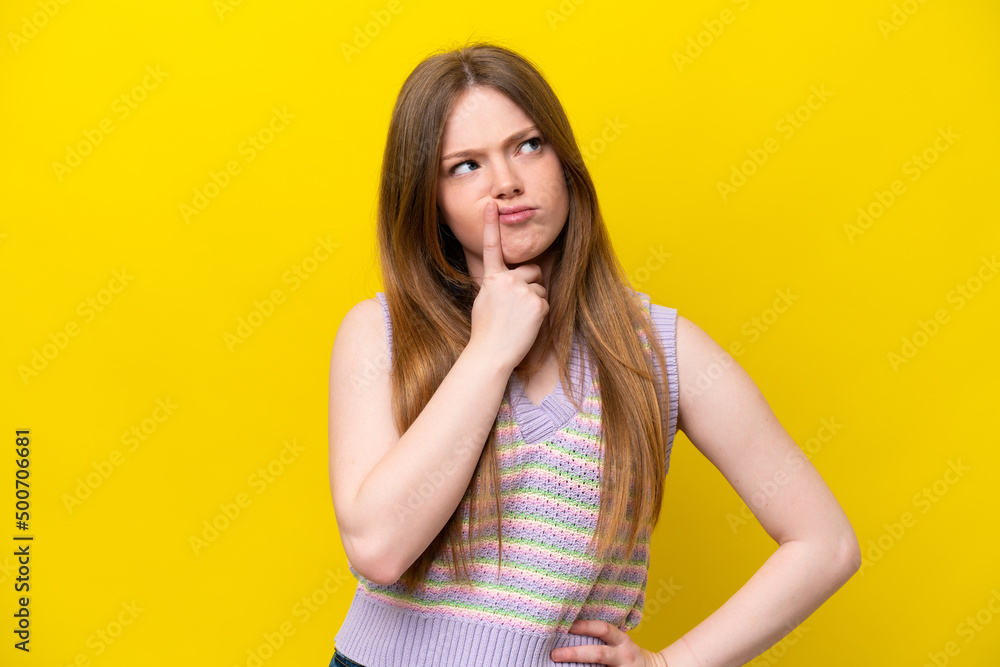 Young caucasian woman isolated on yellow background having doubts while looking up Young caucasian woman isolated on yellow background having doubts while looking up