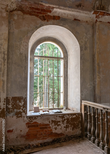 old arched windows in an abandoned church, iron grilles in front of the windows, crumbling window sills and window sills