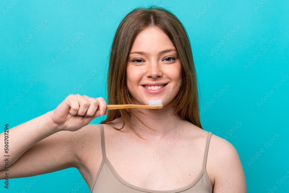Young caucasian woman isolated on blue background with a toothbrush and happy expression Young caucasian woman isolated on blue background with a toothbrush and happy expression