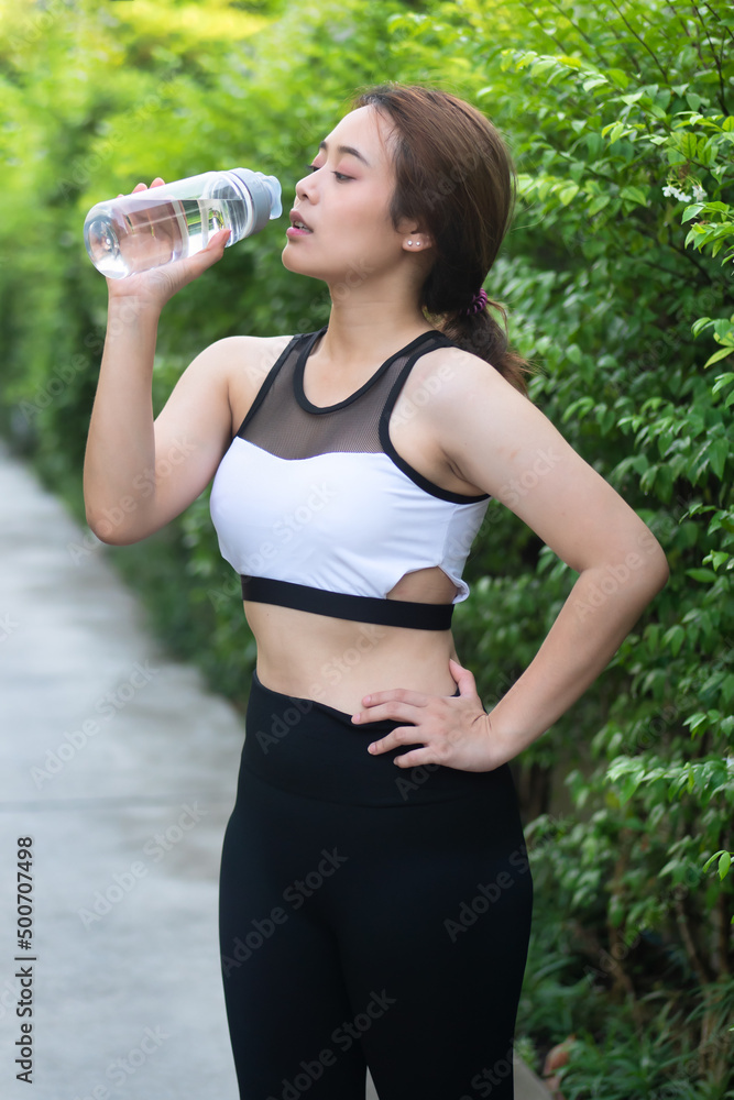 Healthy fitness woman runner drinking water, hydrate herself after jogging, running, working out, exercising, concept image of health care, body care, fitness hydration or rehydration Healthy fitness woman runner drinking water, hydrate herself after jogging, running, working out, exercising, concept image of health care, body care, fitness hydration or rehydration