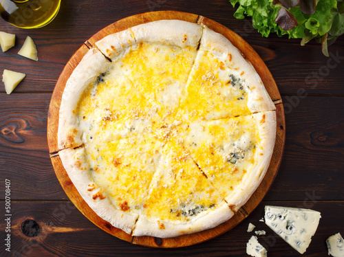 Pizza with 4 cheeses on a wooden background. Cream sauce, mozzarella cheese, Door blue cheese, Maasdam cheese, parmesan cheese. Menu of cafes, pizzeria, restaurant. Close up. Copy space. Fresh dorblu.