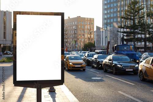 White blank vertical billboard in the city. Backlit sunlight, road collapse. Mock-up.
