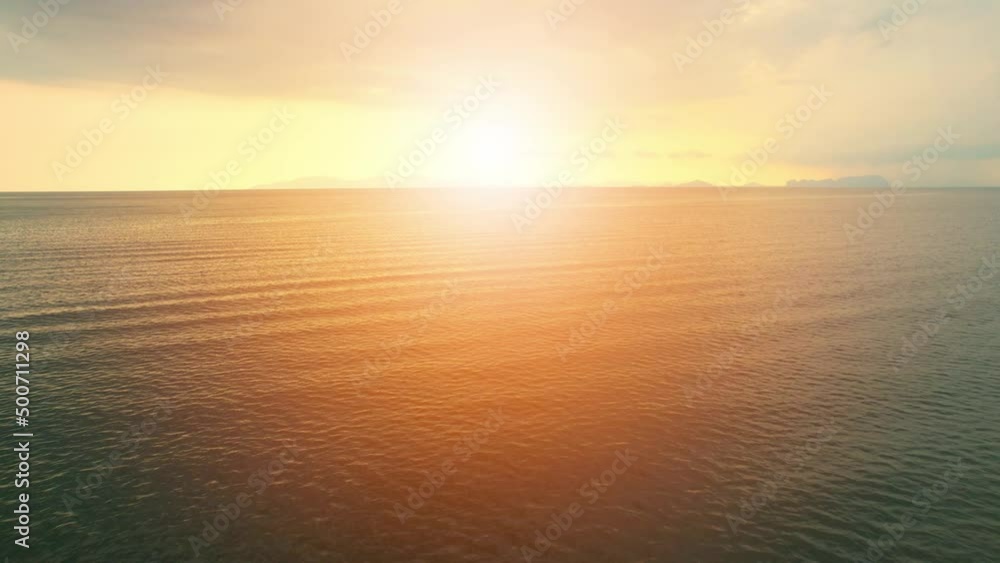 An aerial view of a drone flying over sea waves during sunrise An aerial view of a drone flying over sea waves during sunrise