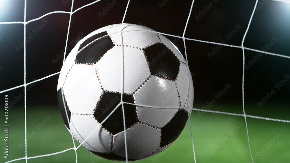 Naklejka premium Soccer ball in goal, isolated on black background