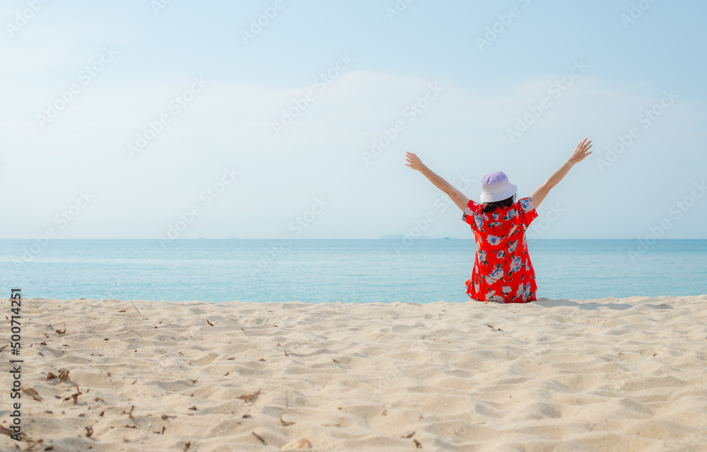 Happy traveller woman in red dress enjoys her tropical beach vacation