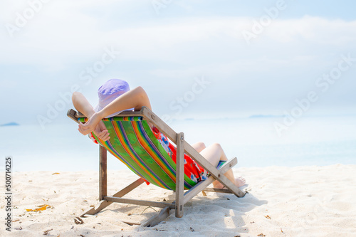Fototapeta Naklejka Na Ścianę i Meble -  Summer beach vacation concept, Asia woman with hat relaxing and arm up on chair beach at Thailand