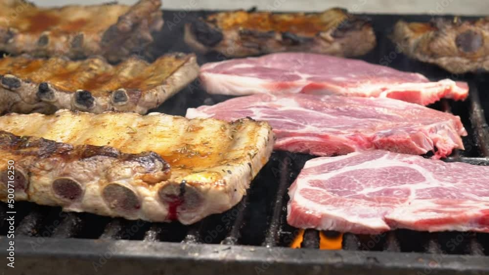 Slowmotion of chef cooking tasty ribs pork on a barbecue grill. Close up of delicious grilled pig cooked in BBQ of garden home at holiday vacations in Spain. Slowmotion of chef cooking tasty ribs pork on a barbecue grill. Close up of delicious grilled pig cooked in BBQ of garden home at holiday vacations in Spain.