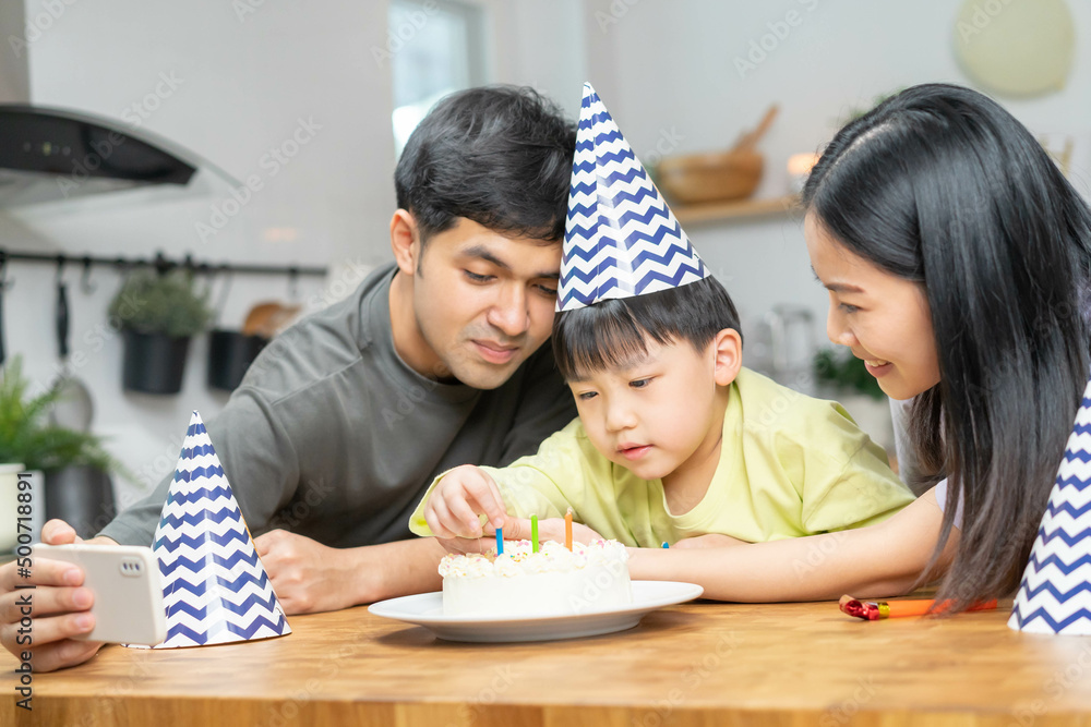 Happy birthday party in family, asian young parent father, mother and little cute boy or child celebrating, using smartphone selfie, take photo and video call during celebration together at home. Happy birthday party in family, asian young parent father, mother and little cute boy or child celebrating, using smartphone selfie, take photo and video call during celebration together at home.