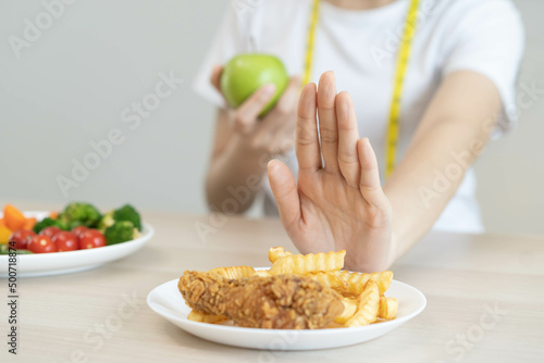 Fototapeta Naklejka Na Ścianę i Meble -  Diet, Dieting asian young woman hand in push out, deny fried chicken, french fried and choose green apple, vegetables salad, eat food for good healthy, health when hungry. Female weight loss people.