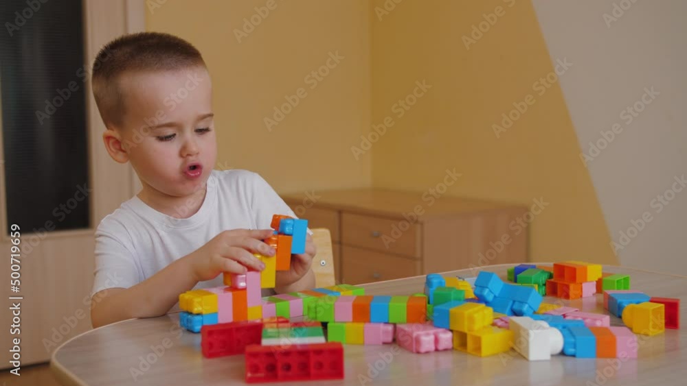 Funny baby boy playing with colorful building blocks, having fun. Cute little child playing with toy plastic constructor at home. Assembling plastic toy bricks, education toys. Funny baby boy playing with colorful building blocks, having fun. Cute little child playing with toy plastic constructor at home. Assembling plastic toy bricks, education toys.