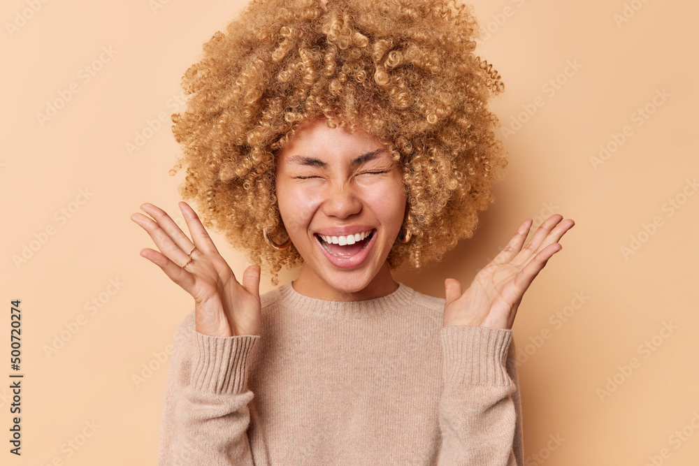 Cheerful optimistic woman keeps palms raised up yells happily closes eyes smils broadly shows white teeth dressed inn casual jumper isolated over brown studio background. Human reactions concept Cheerful optimistic woman keeps palms raised up yells happily closes eyes smils broadly shows white teeth dressed inn casual jumper isolated over brown studio background. Human reactions concept