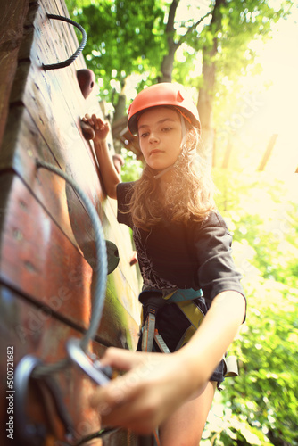 Young girl on the rope park in the forest wearing a helmet