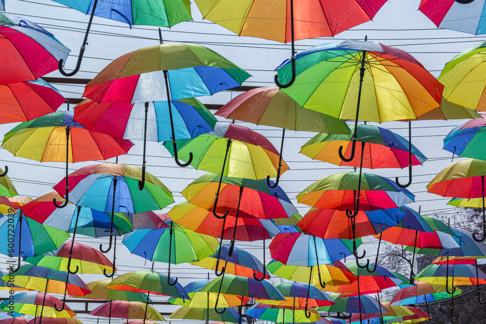 Multi-colored umbrellas over a pedestrian street against the sky on a sunny day