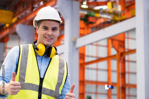 Selective focus at Caucasian men engineer supervisor, wearing safety equipment and ear protection While doing audit for quality and safety control inside of factory area.