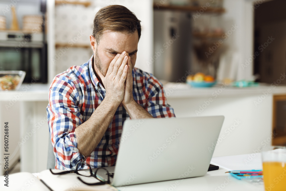 Worried mid adult man working on a computer at home Worried mid adult man working on a computer at home