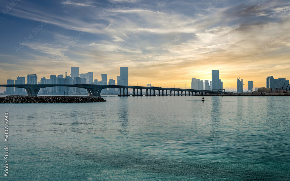 Abu Dhabi, United Arab Emirates - February 2022: Panoramic Abu Dhabi city skyline with a bridge during sunset. Abu Dhabi attracts 10 million people annually.