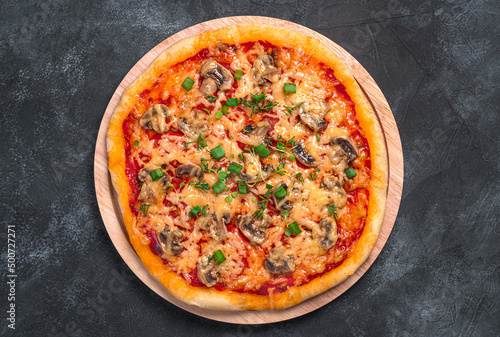 Pizza with vegetables, cheese and fresh herbs on a black background.
