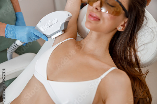 Armpits laser epilation for female client by modern cosmetology device. Hair removal photo