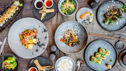 assorted china dishes on table, fried spring rolls with duck, pork with sour sweet sauce, sushi, rolls,shrimps in wasabi sauce, beef with vegetables, broccoli top view