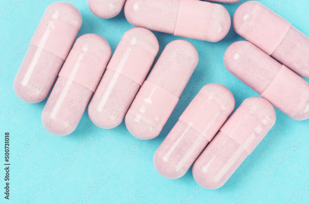 Pink capsule pills on blue background. Pink capsule pills on blue background.