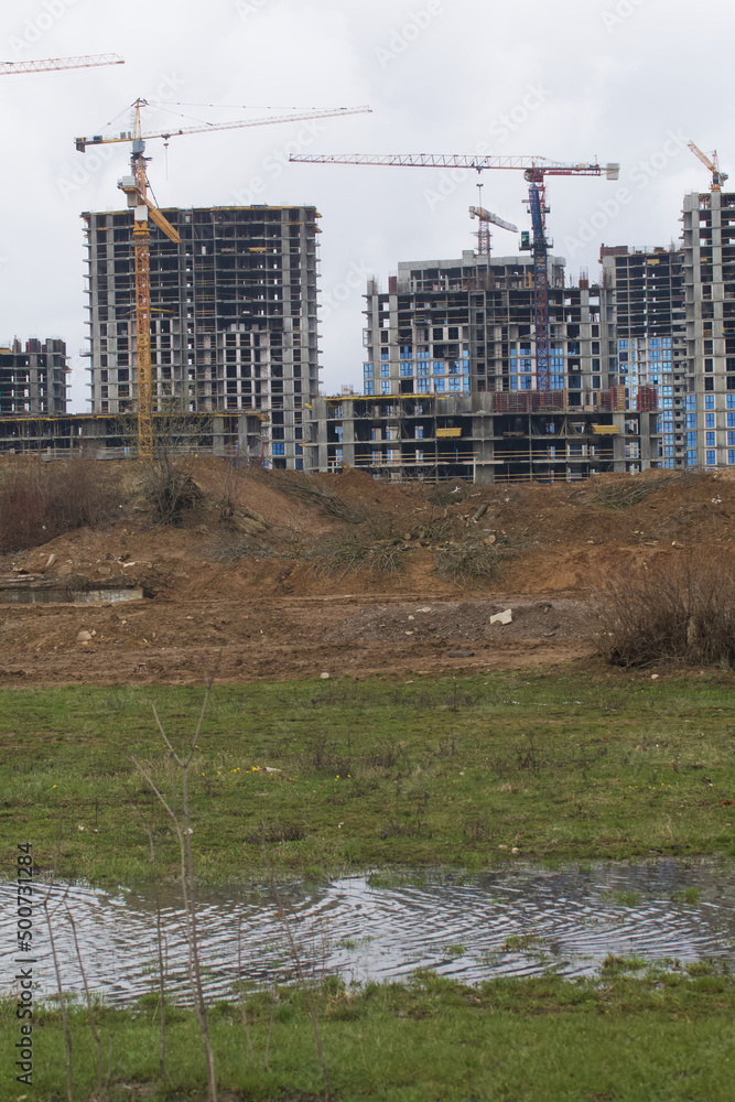 Obraz premium Construction of multi-storey buildings. Modern multi-storey building. Houses with reinforced concrete frame. Work construction cranes.