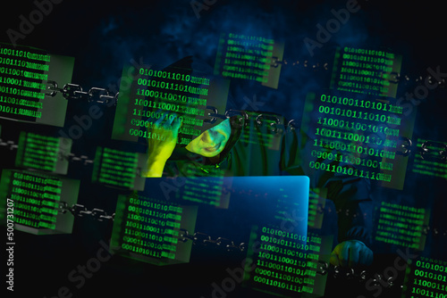 Image of a man in a black hoodie pointing to the screen of a laptop computer at home and remotely controlling it, under green glowing binary data in a glass cube on chains.
