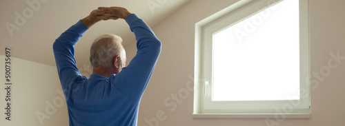 Canvas Print Senior man in pajamas waking up and stretching in the morning