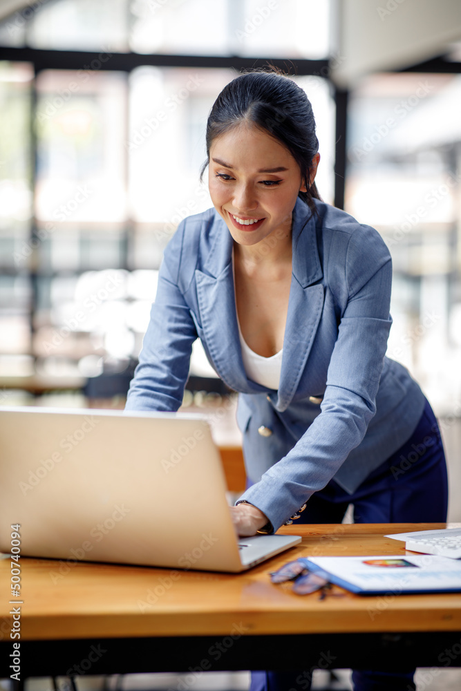 Asian Businesswoman Using laptop computer and working at office with calculator document on desk, doing planning analyzing the financial report, business plan investment, finance analysis concept. Asian Businesswoman Using laptop computer and working at office with calculator document on desk, doing planning analyzing the financial report, business plan investment, finance analysis concept.