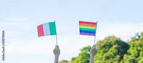 Photography hands showing LGBTQ Rainbow and Italy flag on nature background