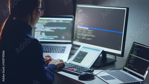 Young Asian woman, developer programmer, software engineer, IT support, wearing glasses working hard at nitght overtime on computer to check coding in bugging system. Back view
