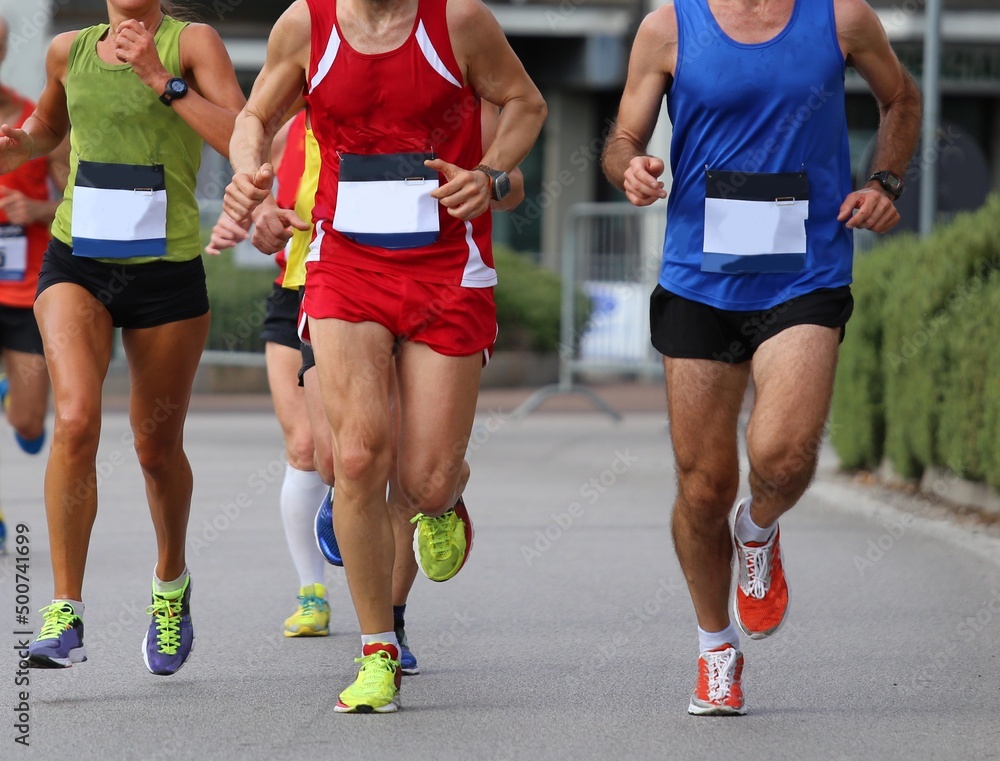 athletic runners during the foot race in the city on the asphalt road and sportswear and running shoes