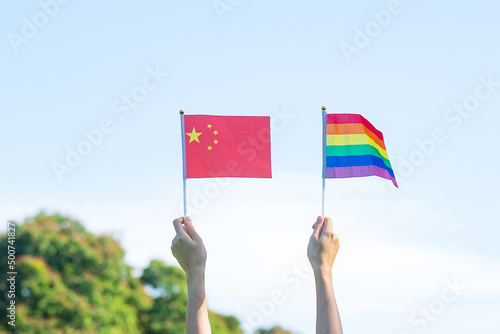 Wall Mural hands showing LGBTQ Rainbow and China flag on nature background