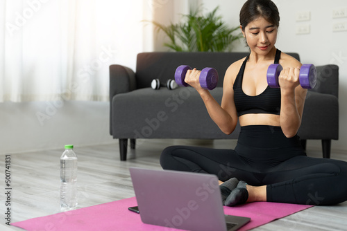 Young asian woman doing fitness exercises at home through virtual class