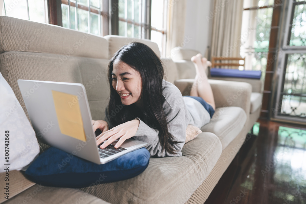Young adult southeast asian woman stay and working at home using laptop computer on sofa Young adult southeast asian woman stay and working at home using laptop computer on sofa