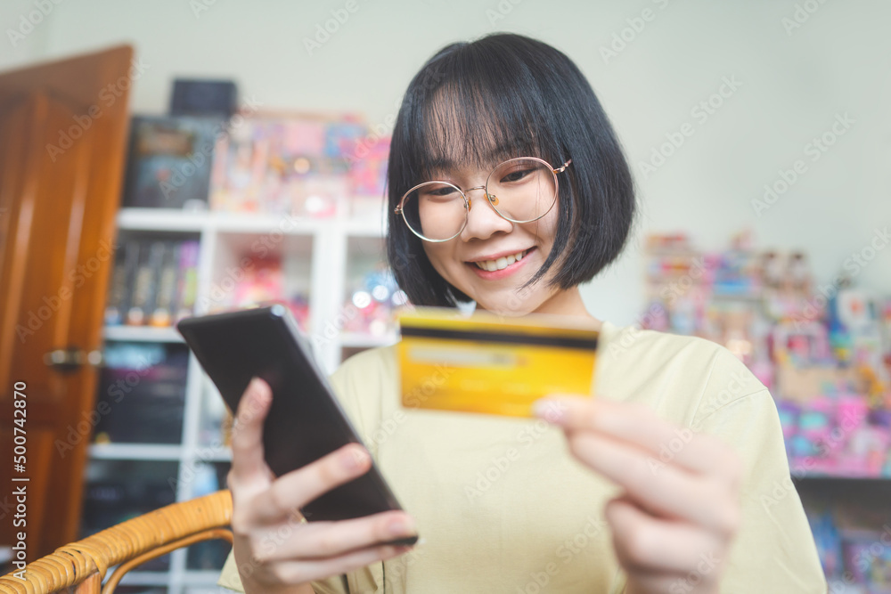 Young adult asian woman using smartphone and credit card make transaction via digital application Young adult asian woman using smartphone and credit card make transaction via digital application