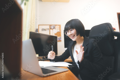 Young adult asian woman using laptop computer for video call work at home on day.