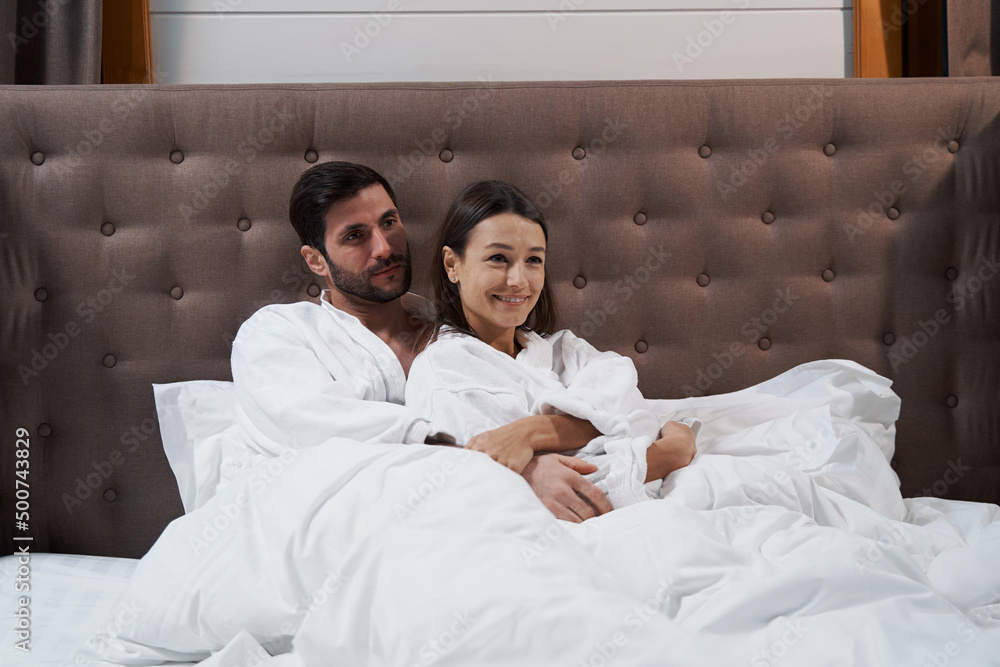 Fototapeta premium Man hugging his wife in bed of hotel room