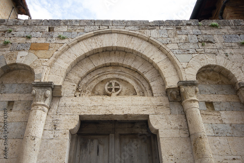 Medieval vaulted arch with cross above the door jamb in the historic village of Monteriggioni