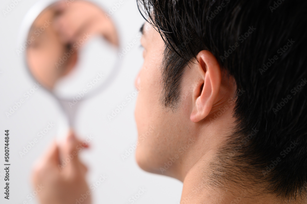 Obraz premium 手鏡で顔をチェックする男性 メンズ美容