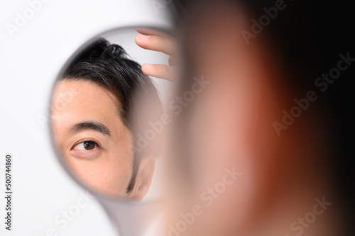 手鏡で顔をチェックする男性 メンズビューティー