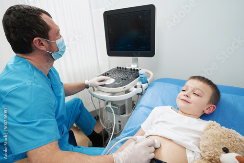 Caring doctor examining the small boy with an ultrasound