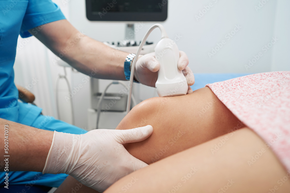 Medical worker performing an ultrasound on the patient knee joint Medical worker performing an ultrasound on the patient knee joint