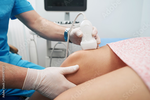 Medical worker performing an ultrasound on the patient knee joint