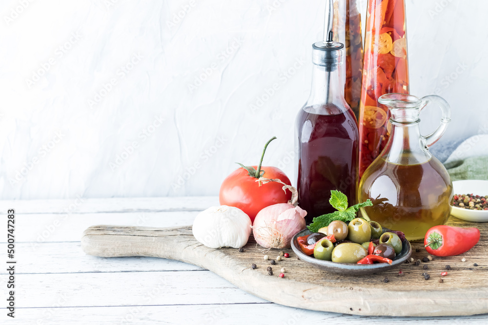 Oil and red wine vinegar in glass bottles with olives and peppercorns. Oil and red wine vinegar in glass bottles with olives and peppercorns.