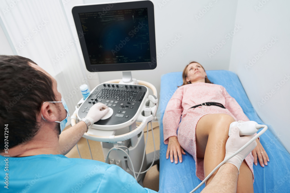 Orthopedist doctor doing ultrasound examination of patient knee in his office Orthopedist doctor doing ultrasound examination of patient knee in his office