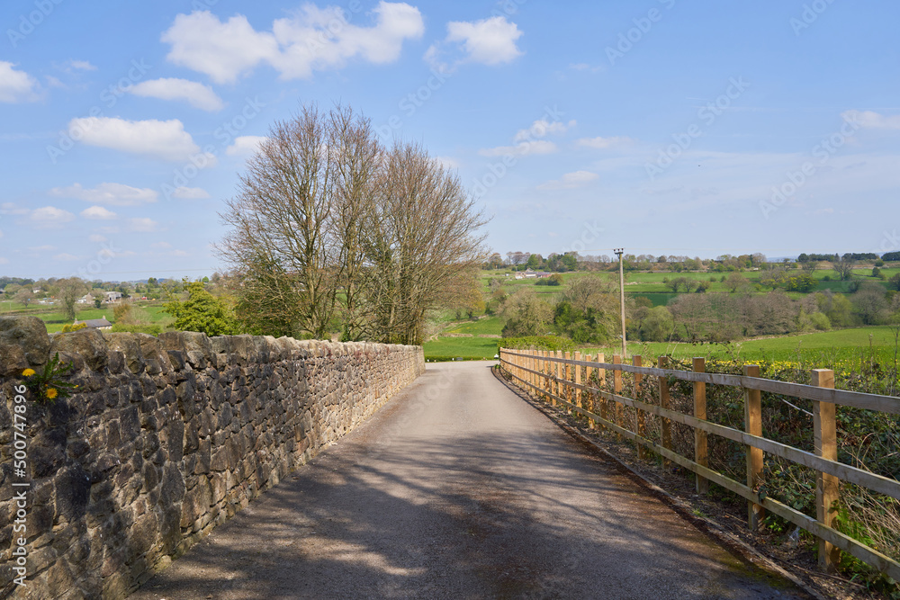 Country lane with stone wall and wooden fence